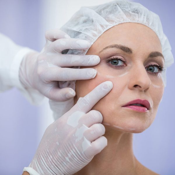 Close-up of doctor examining female patients face for cosmetic treatment